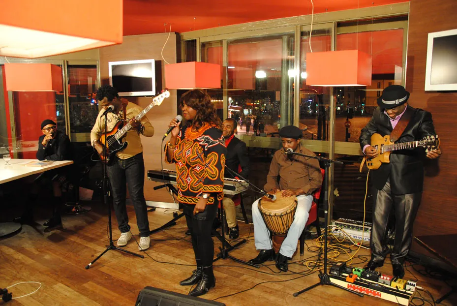 Angélina Tezanou chante en toghu camerounais, entourée de son groupe sur scène.