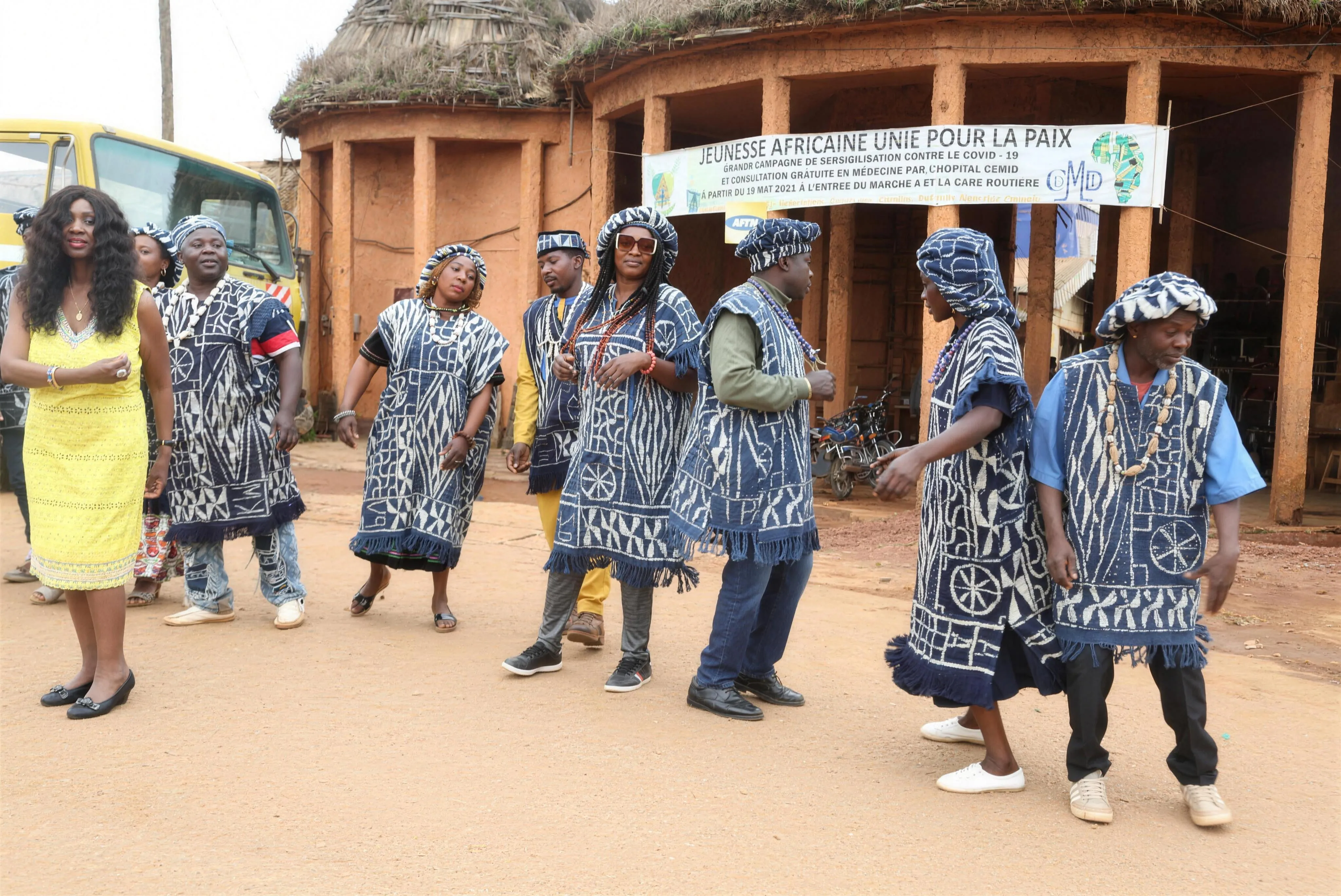 Angélina Tezanou en robe jaune parmi un groupe en tenue Toghu lors d'une procession dans un village de l'ouest camerounais.